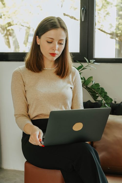 Free A woman sitting on a couch, focused on her laptop in a comfortable indoor environment. Stock Photo