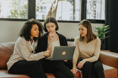 Free Three women working together on a laptop indoors. Teamwork and collaboration. Stock Photo