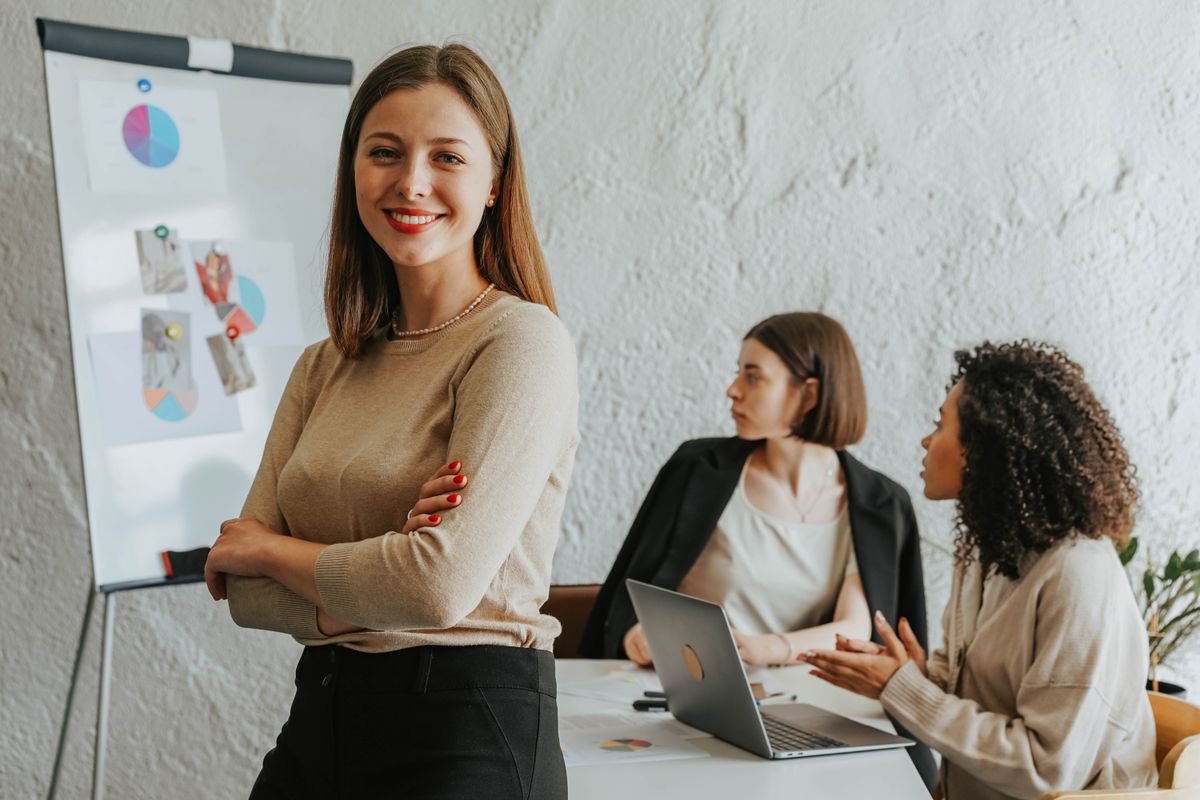 Confident woman smiling in a modern office setting with colleagues at work