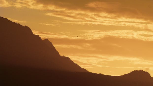 A breathtaking mountainous silhouette against a dramatic golden sunset sky.