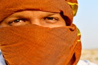 沙漠背景下，一名男子戴着沙特阿拉伯的传统围巾，眼睛特写