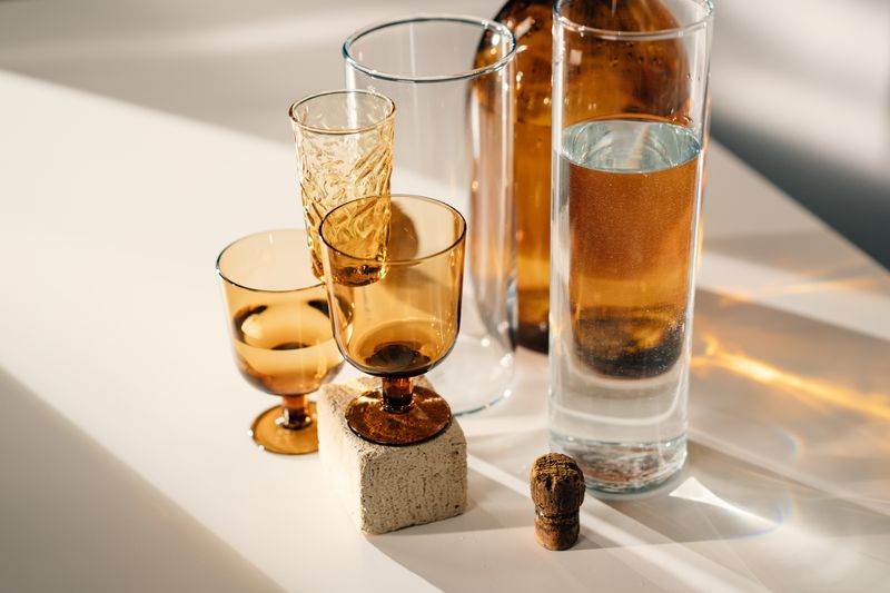 Amber and clear glassware casting long shadows on a pale table — photo by cottonbro studio on Pexels