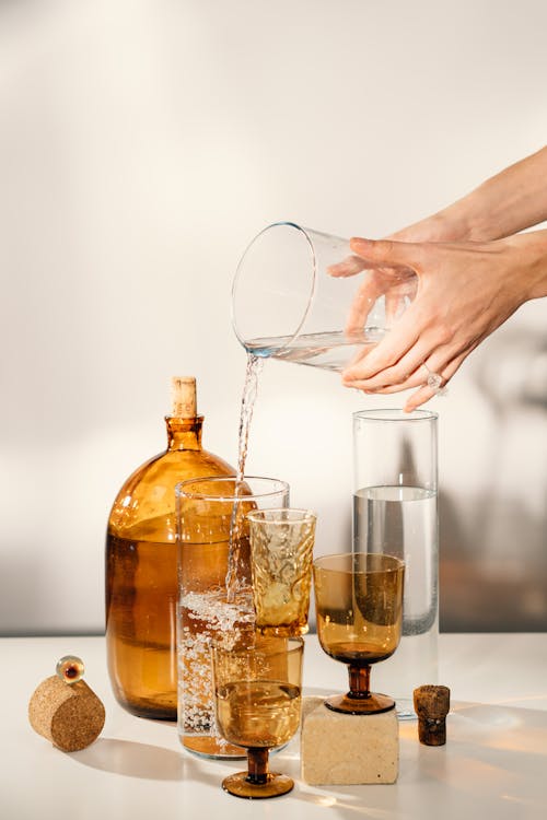 Person Pouring Water on Clear Drinking Glass