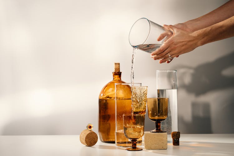 Person Pouring Water On Clear Glass