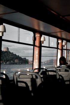 View through ferry windows showcasing a scenic river and bridge.