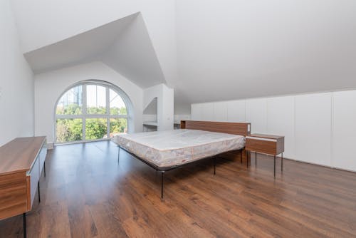 Bed with Wooden Headboard Near Arched Window