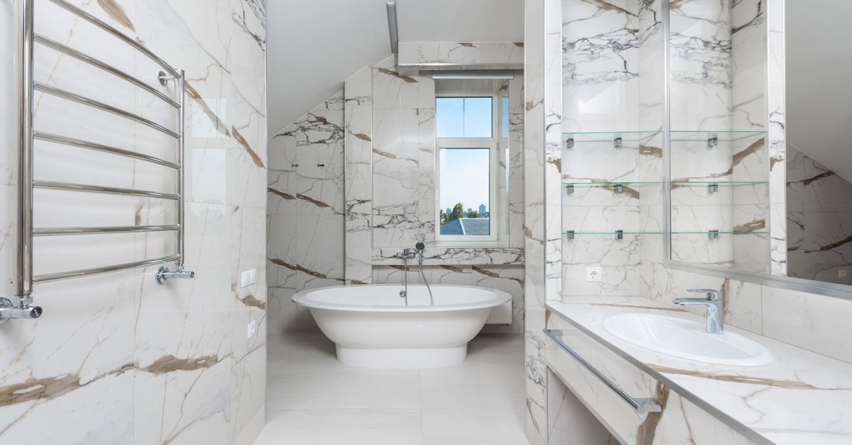 Spacious and elegant marble bathroom featuring a modern bathtub, sink, and glass window.