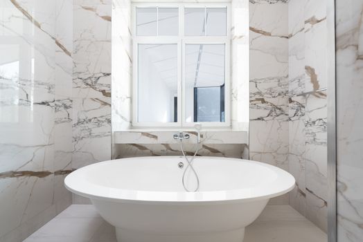 Luxurious marble bathroom featuring a sleek freestanding bathtub and modern design elements.