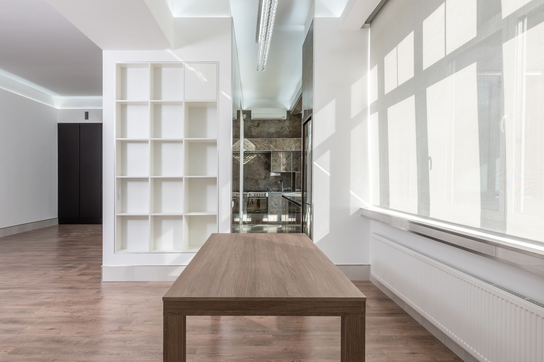 Spacious minimalist interior with wooden table and ample natural light.