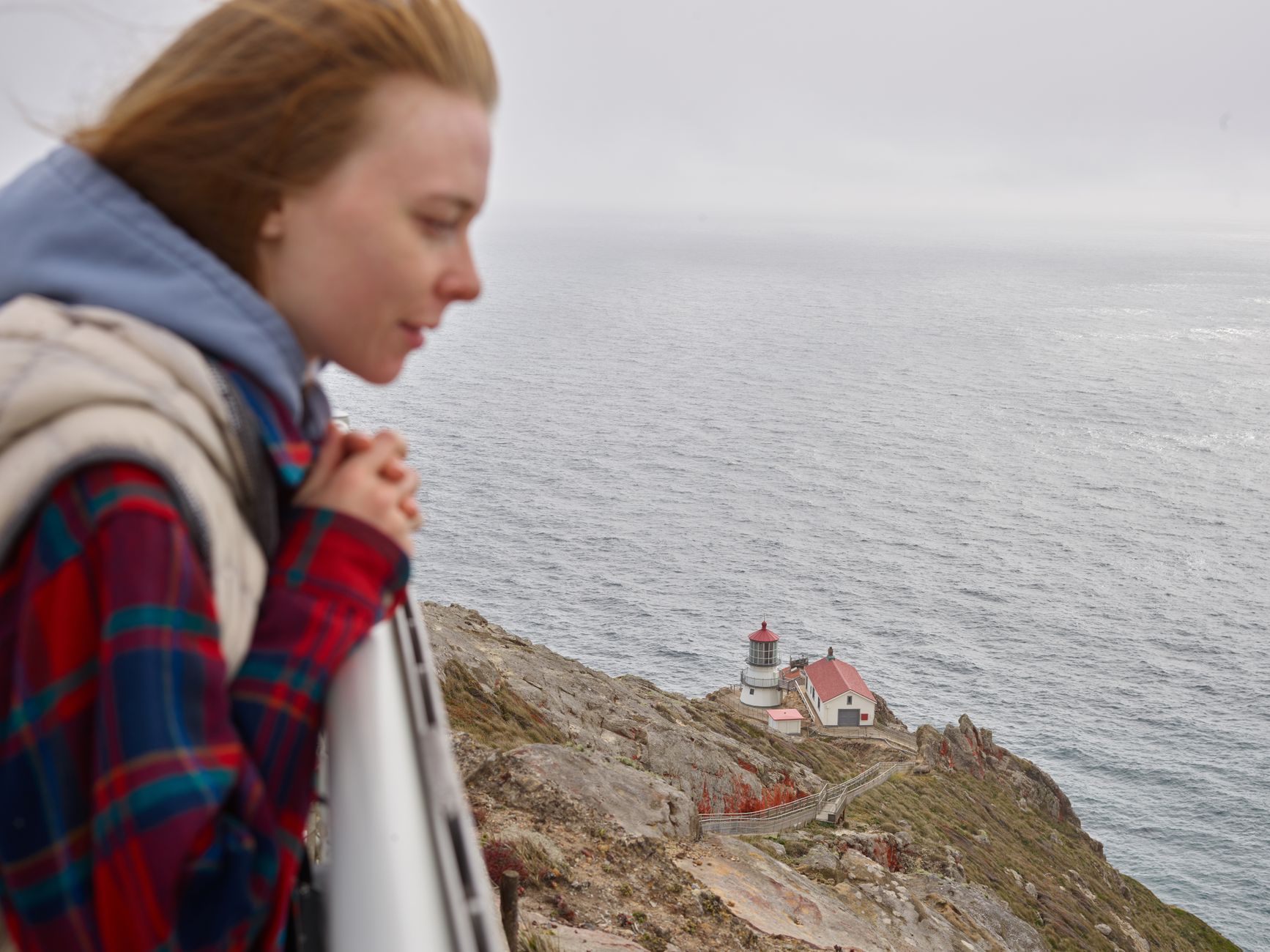 14 Lighthouses You Can Actually Spend the Night In 1 Woman overlooking Point Reyes Lighthouse and Pacific Ocean, embracing nature.