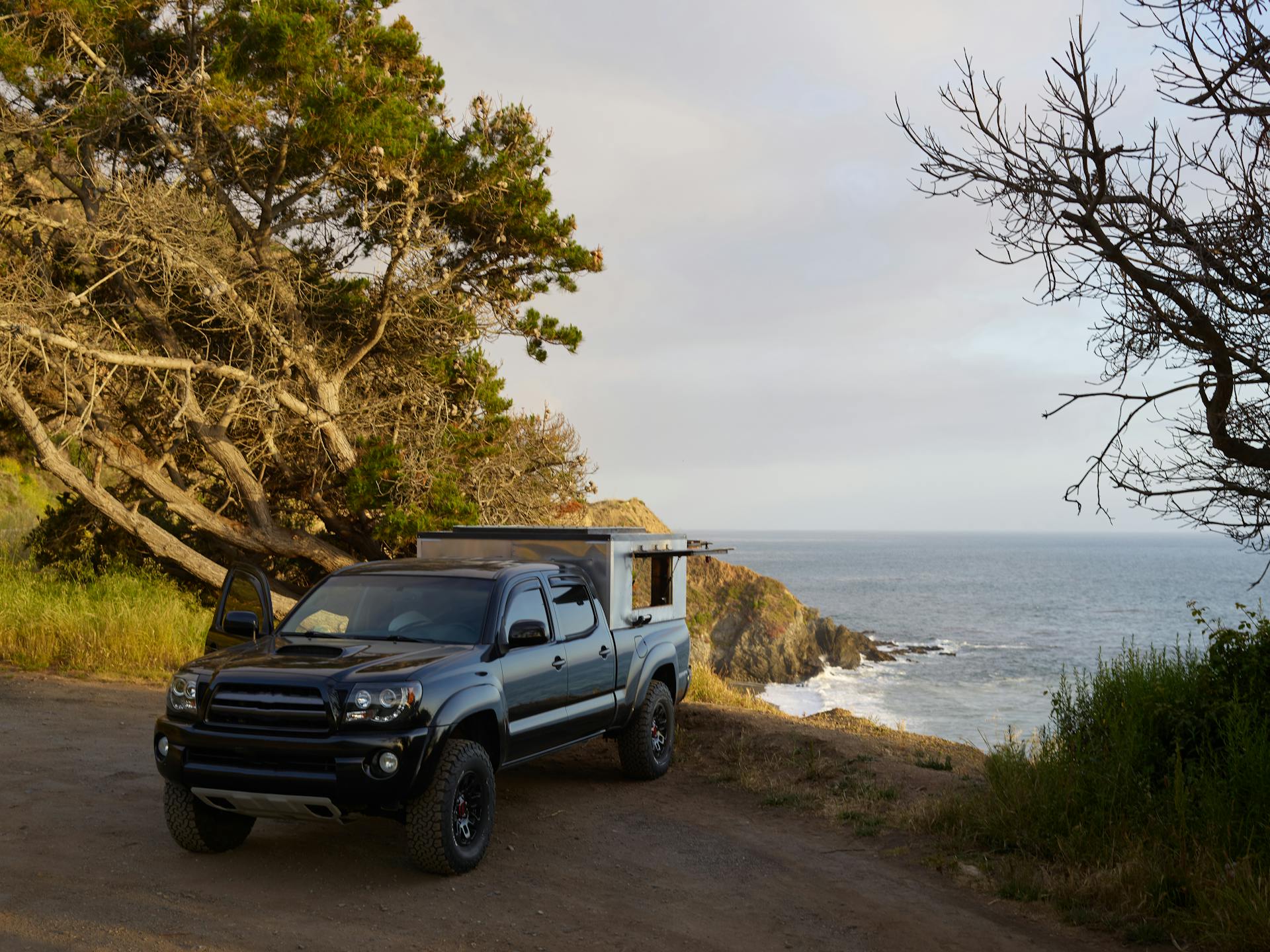 Pickup truck parked by a scenic seaside cliff, perfect for a serene road trip adventure.