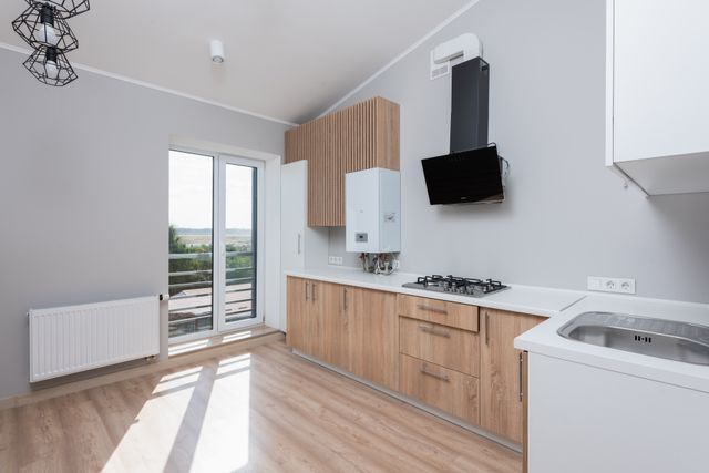 Sunlit kitchen with wooden cabinets and a balcony door — photo by Max Vakhtbovych on Pexels