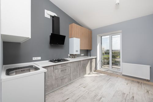 Free Sleek and modern kitchen with minimalist design, light colors, and large windows. Stock Photo
