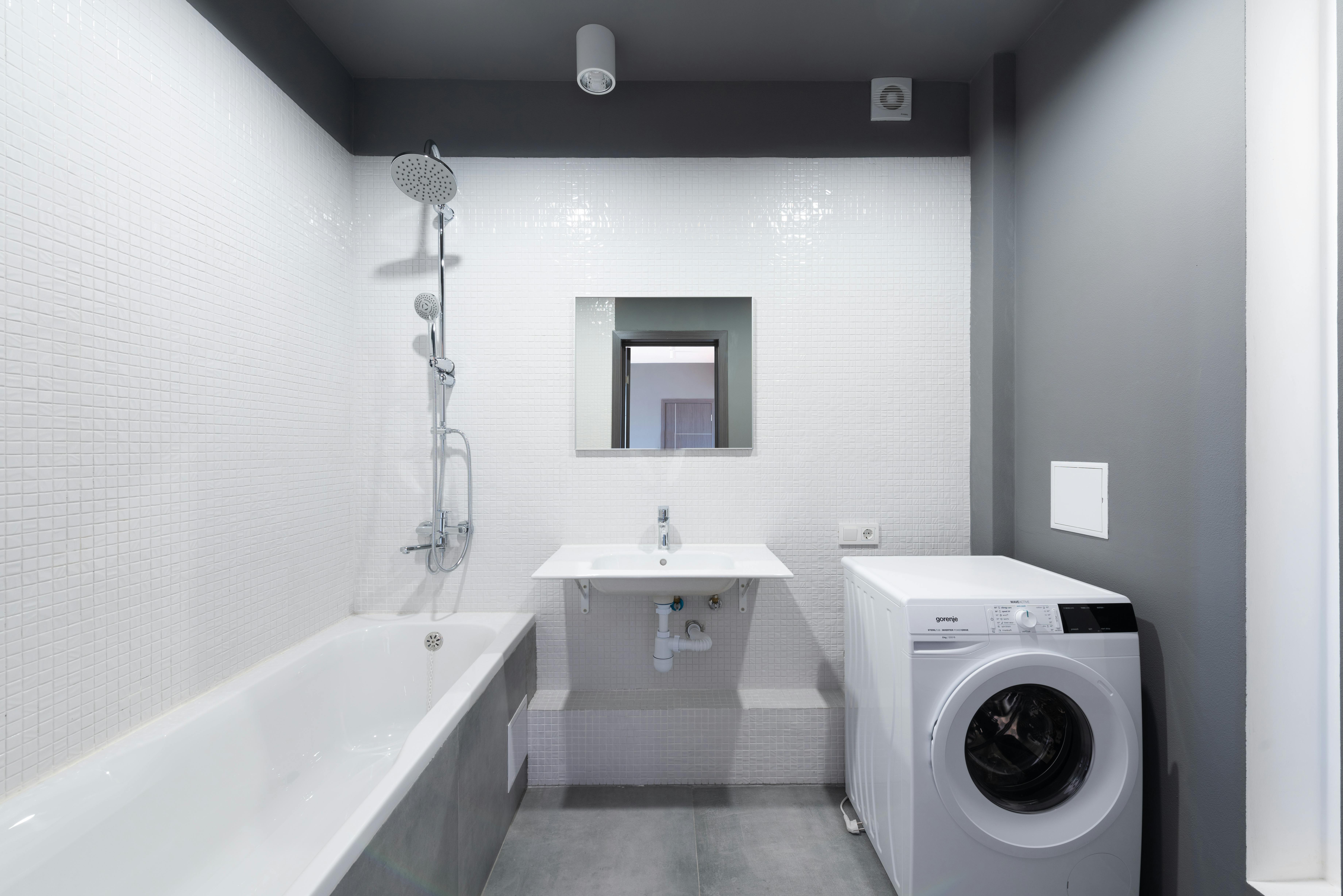 Badezimmer mit integrierter Waschmaschine unter Arbeitsplatte und Wandregalen mit Körben