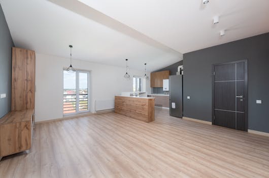 Spacious, bright, and empty open-plan kitchen and living area with wooden flooring.