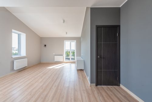 Free Spacious empty room with wooden flooring and large windows for ample natural light. Stock Photo