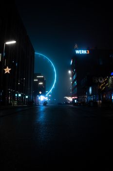 A stunning night view of München featuring an illuminated Ferris wheel and city lights.