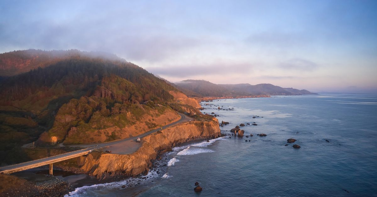 A breathtaking aerial view of the scenic Westport coastline at sunset with ocean and rugged cliffs.