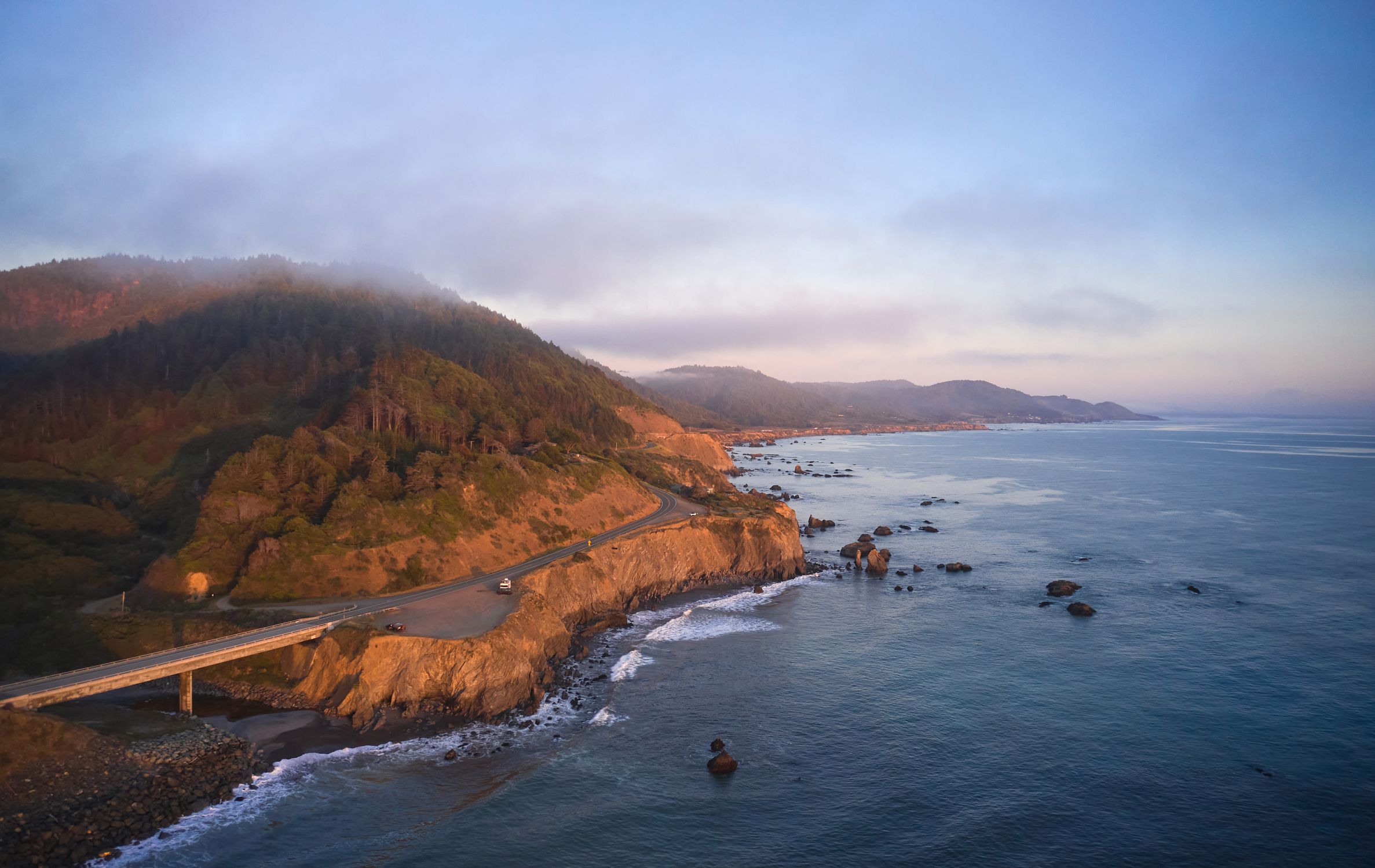 A breathtaking aerial view of the scenic Westport coastline at sunset with ocean and rugged cliffs.