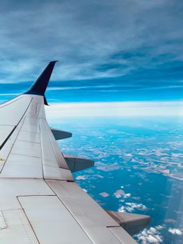 A breathtaking view from an airplane window showcasing the wing, blue sky, and white clouds.