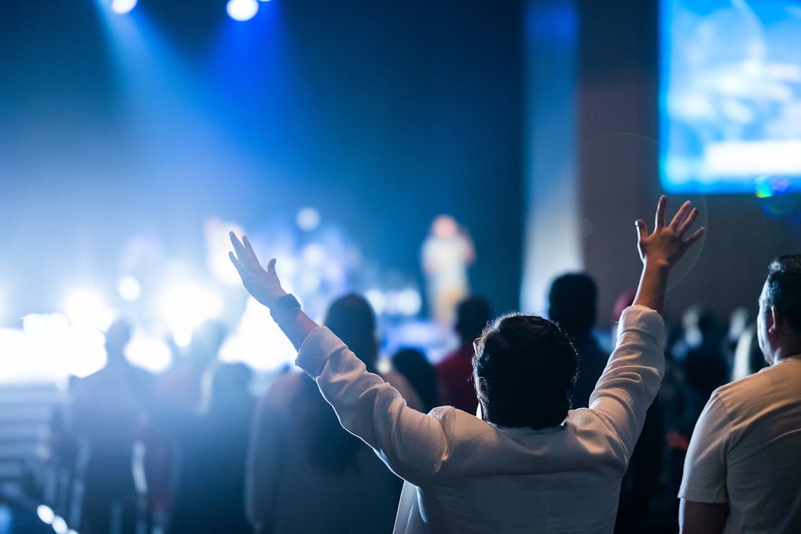 Man in White Coat Watching a Concert with Arms Raised · Free Stock Photo