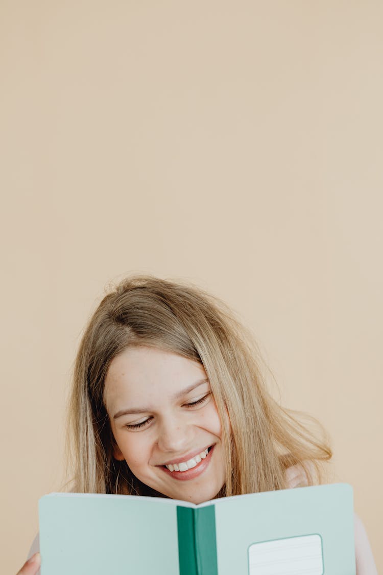 A Smiling Teenager Reading A Book