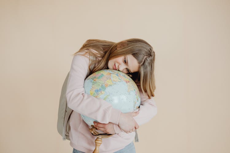 A Young Girl Hugging A Globe