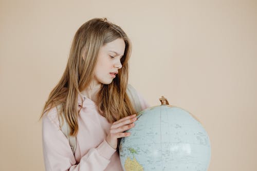 Woman in Pink Hoodie Shirt Holding Desk Globe