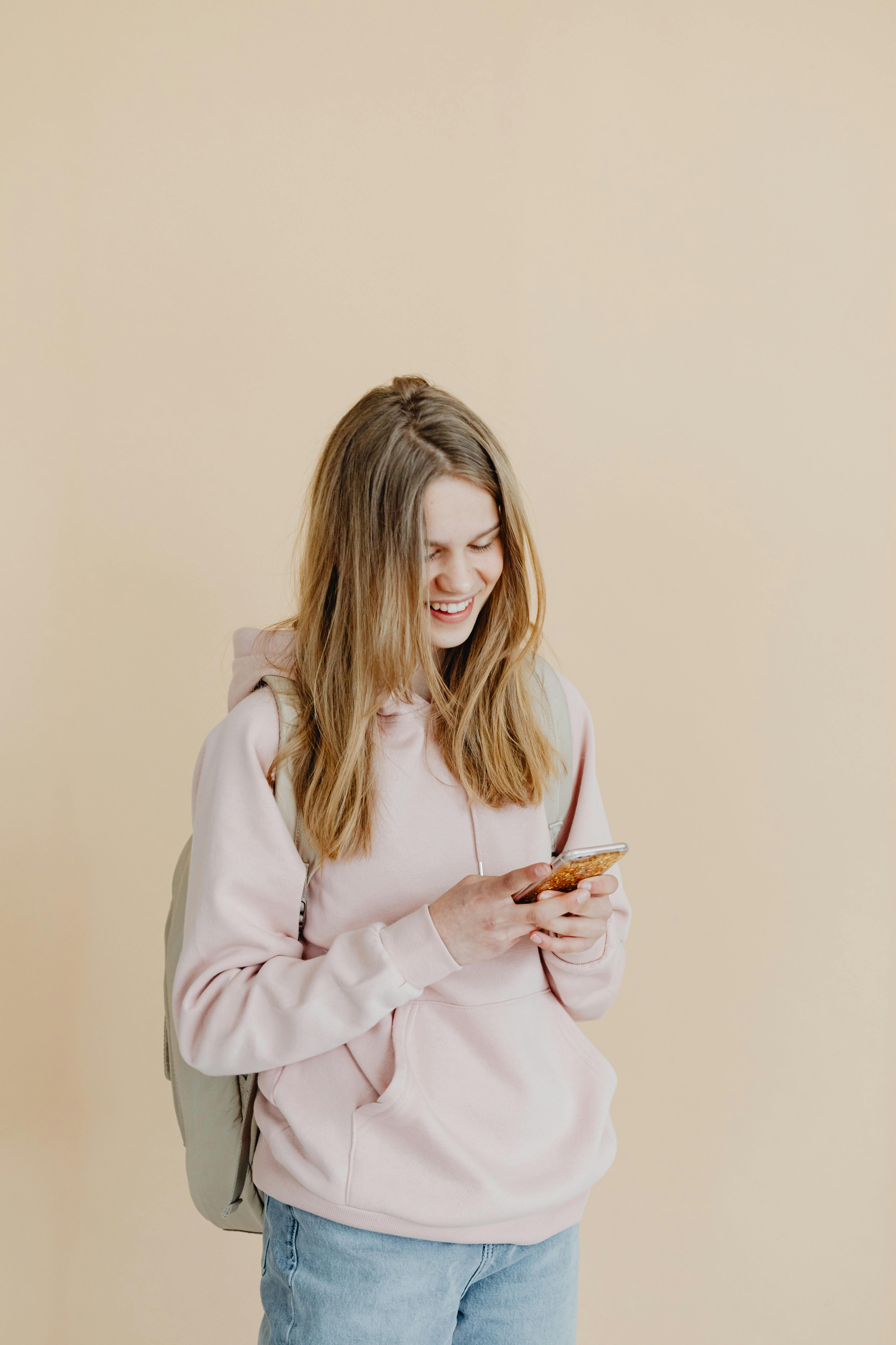 girl in pink hoodie holding a smartphone