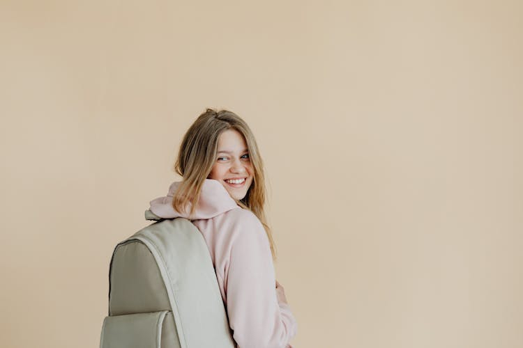 A Woman In Beige Hoodie Carrying A Backpack