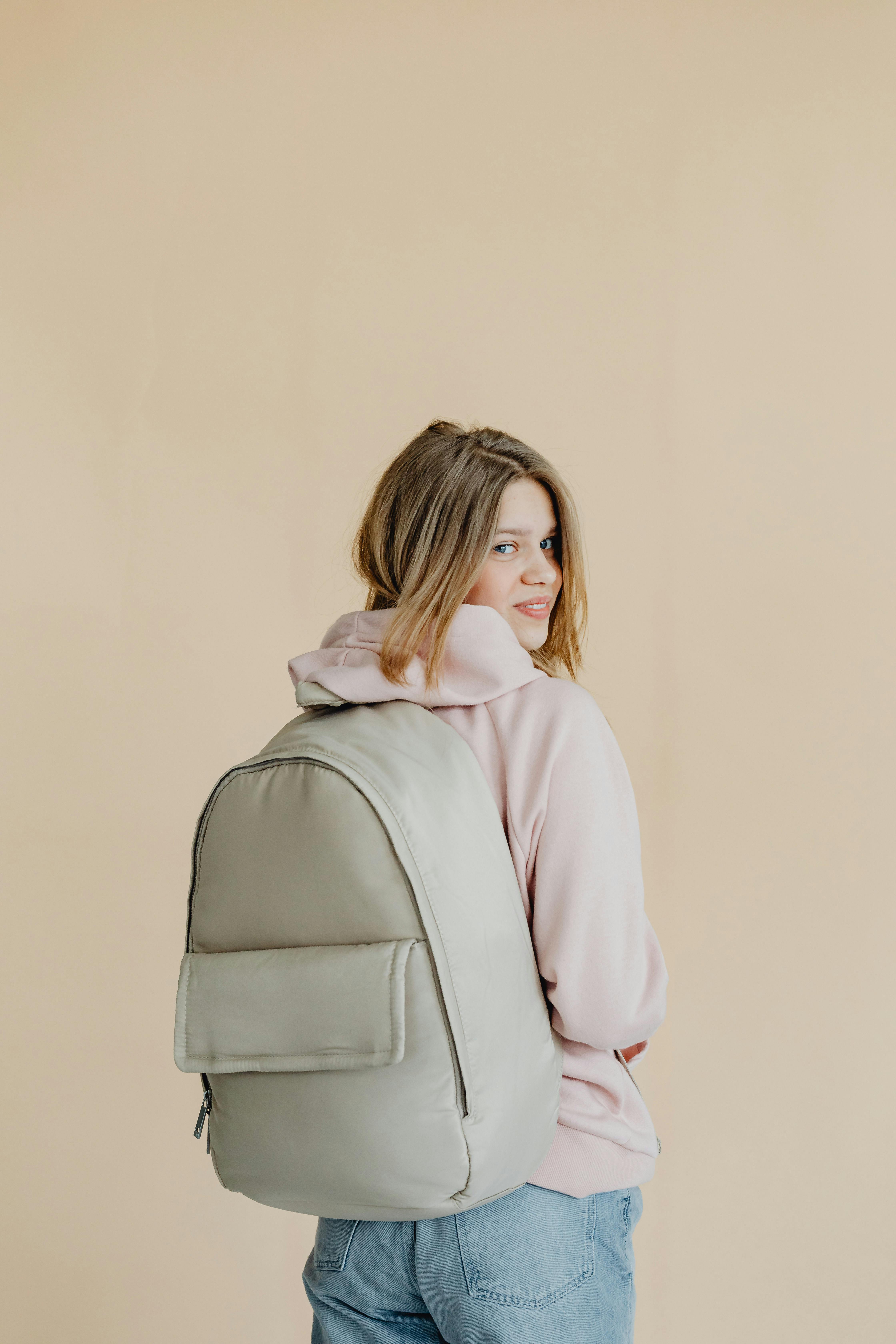 a woman in beige hoodie carrying a backpack