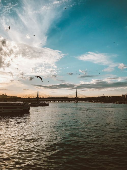 Free Beautiful cityscape featuring a bridge and calm waters under a vibrant sunset sky. Stock Photo
