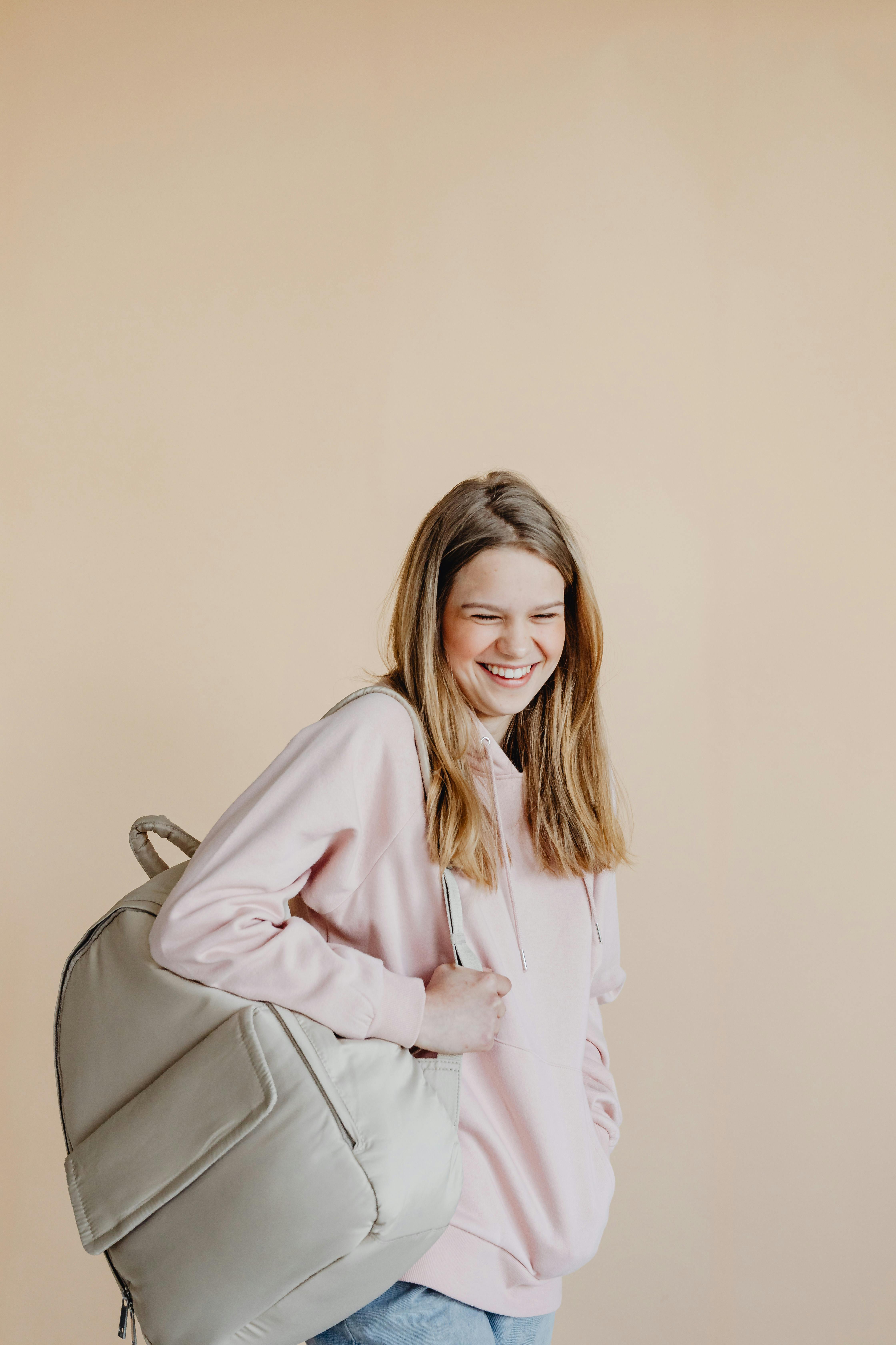 a woman in beige hoodie carrying a backpack