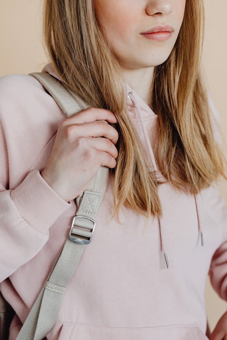 A Girl Holding The Strap Of Her Backpack