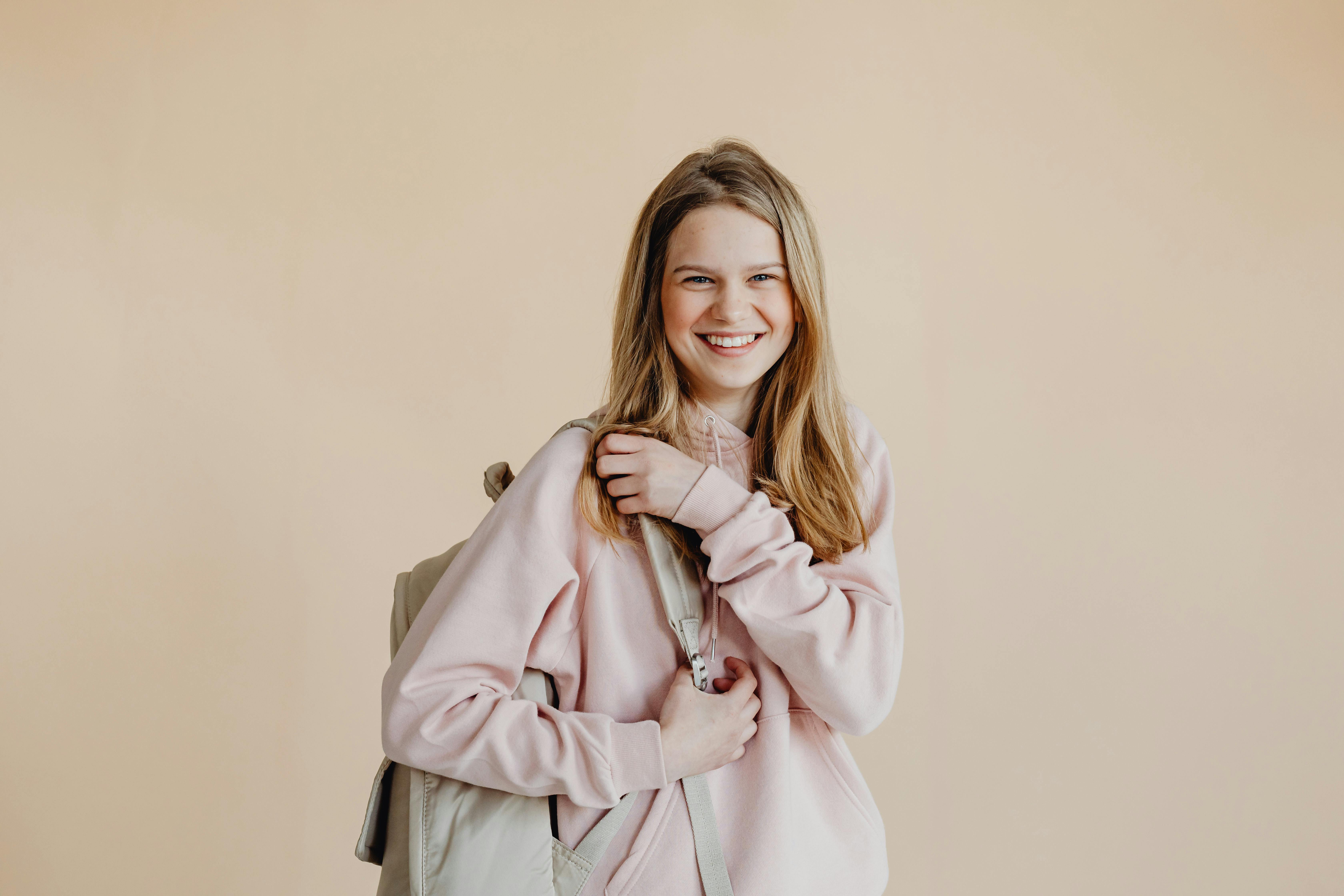 a smiling woman in pink sweater carrying her backpack