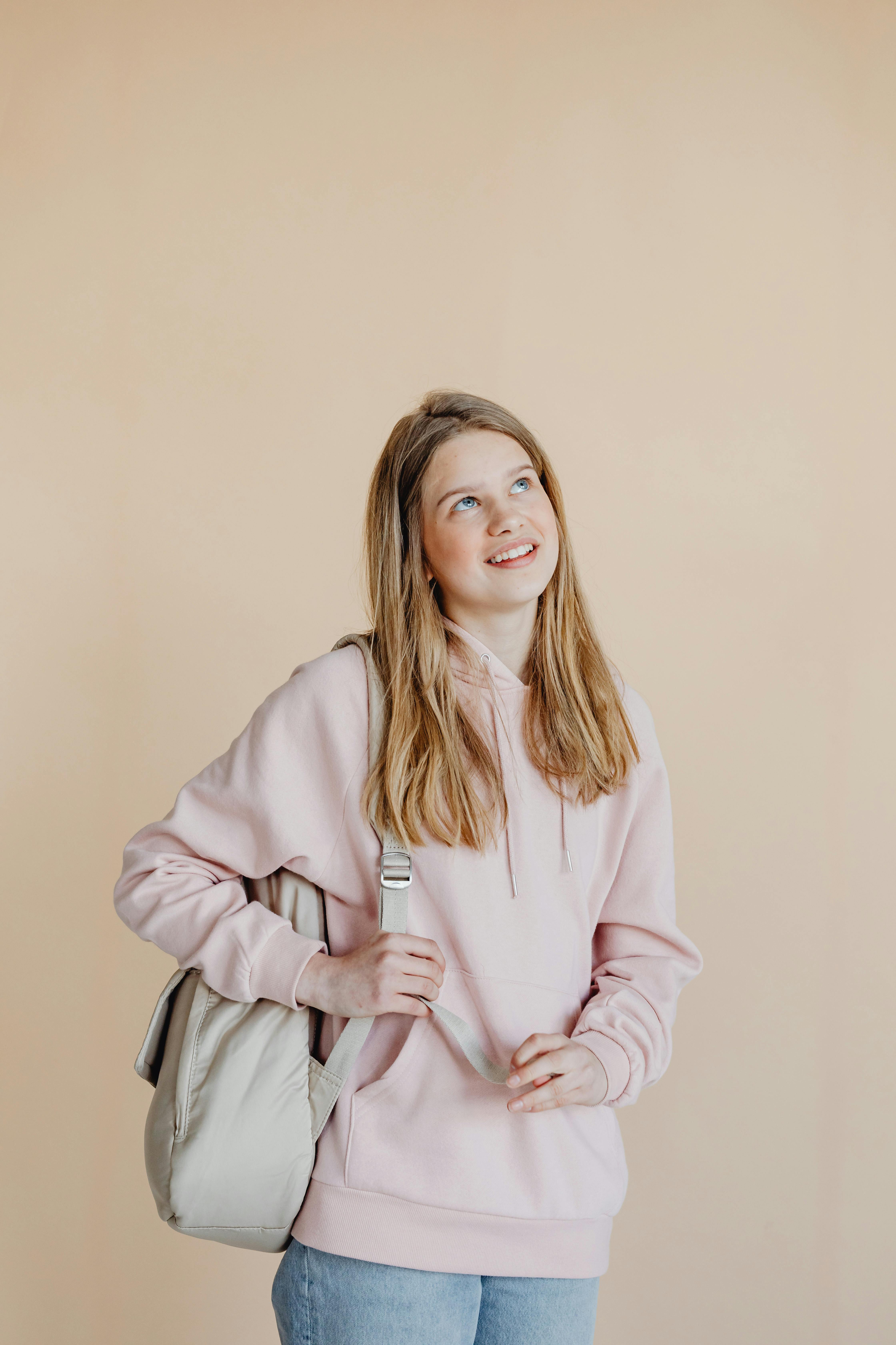 a woman in beige hoodie carrying a backpack