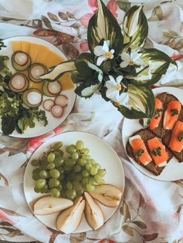 A vibrant brunch display featuring fresh fruits, salmon toasts, and floral decor.