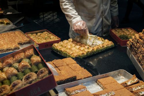 Free From above of crop anonymous male in uniform and gloves serving tasty baked dessert in plastic container in bakery Stock Photo