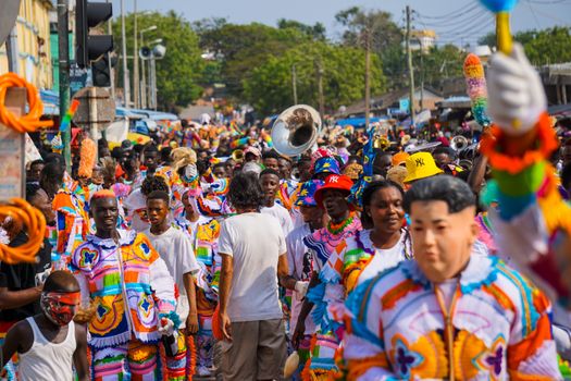 A lively street parade featuring people in colorful costumes, celebrating cultural festivities.