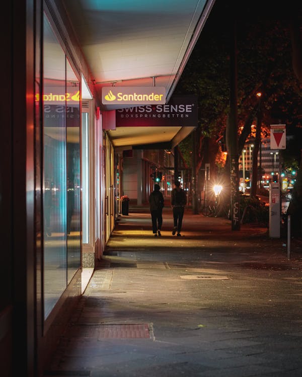 Free Two People Walking on Sidewalk during Night Time Stock Photo