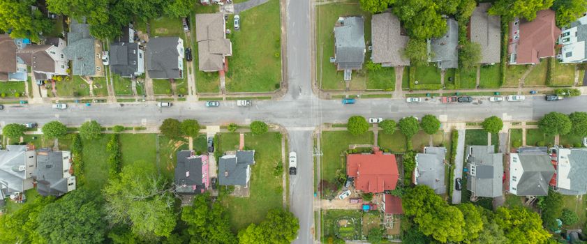 Aerial photo capturing an intersection in a suburban neighborhood with houses and greenery.