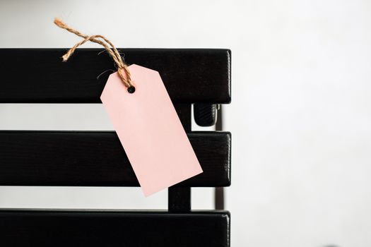 Minimalist image of a pink tag attached to a wooden surface with twine.