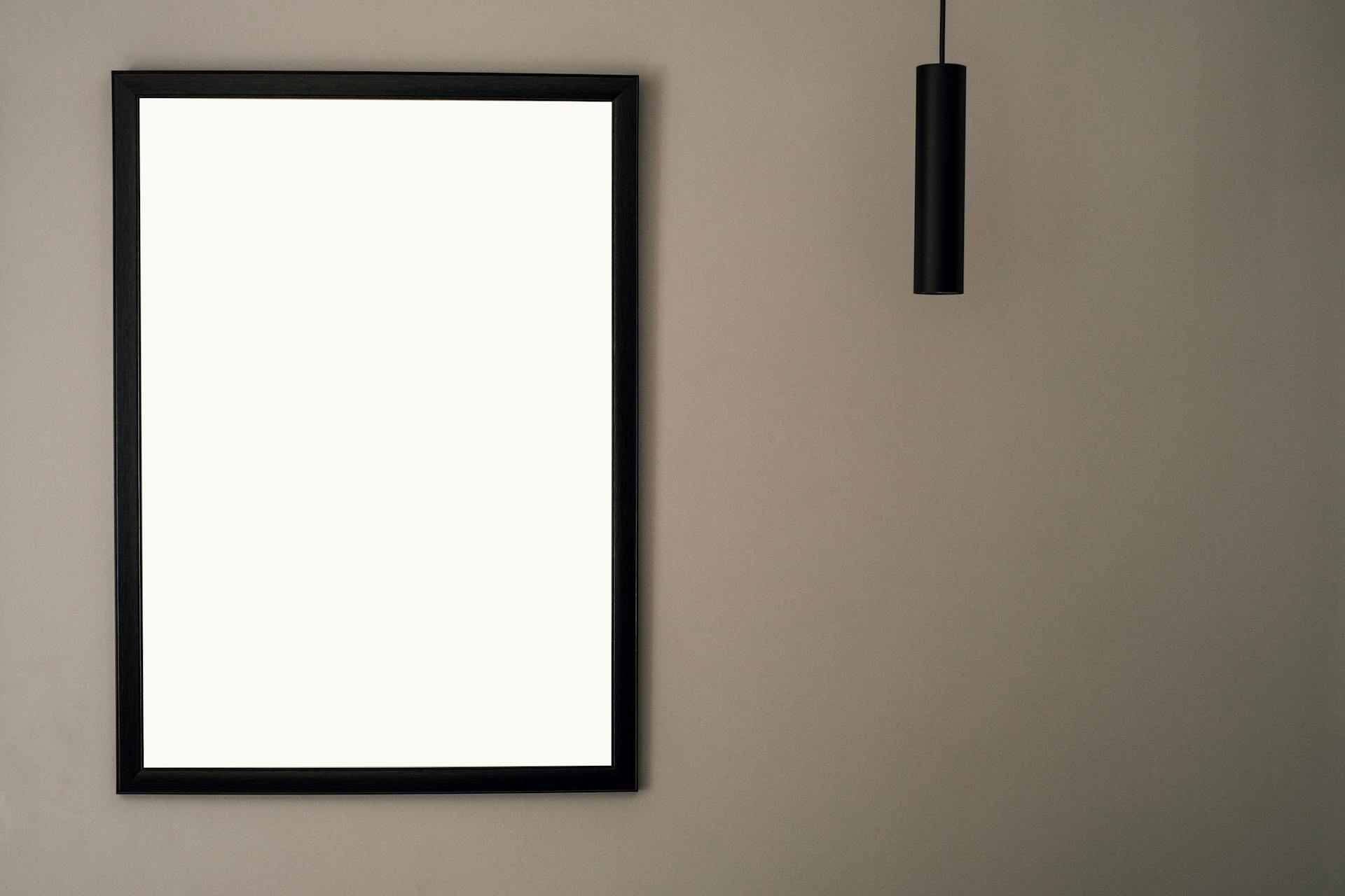 A minimalist picture frame on a neutral wall with hanging light and ample copy space.