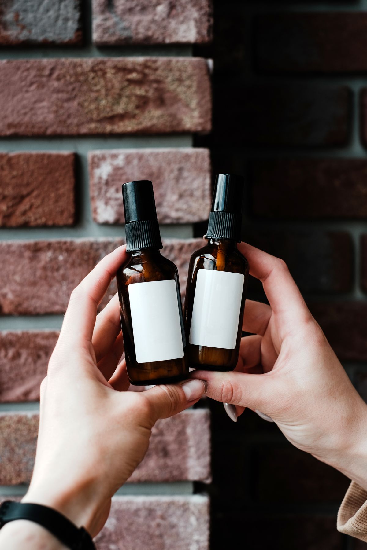 Hands holding two amber bottles with brand labels