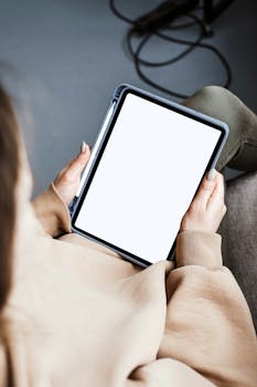 A person holding a tablet with a blank screen, ideal for mockups and presentations.