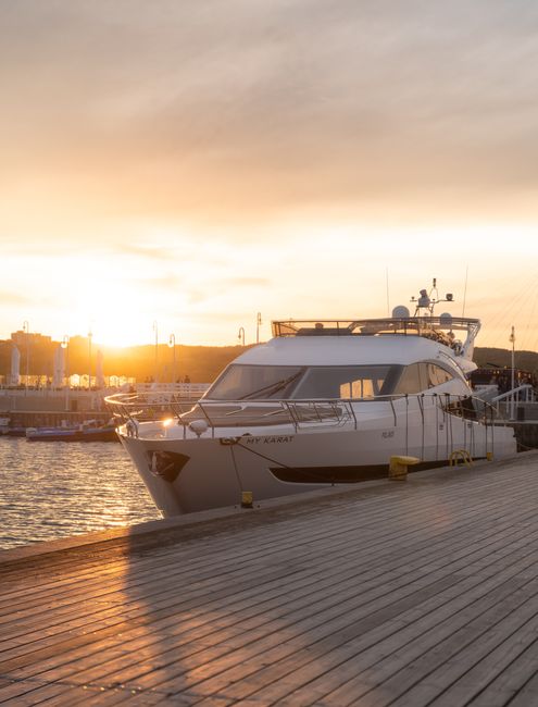 Serene view of a luxury yacht docked at Sopot harbor at sunset.