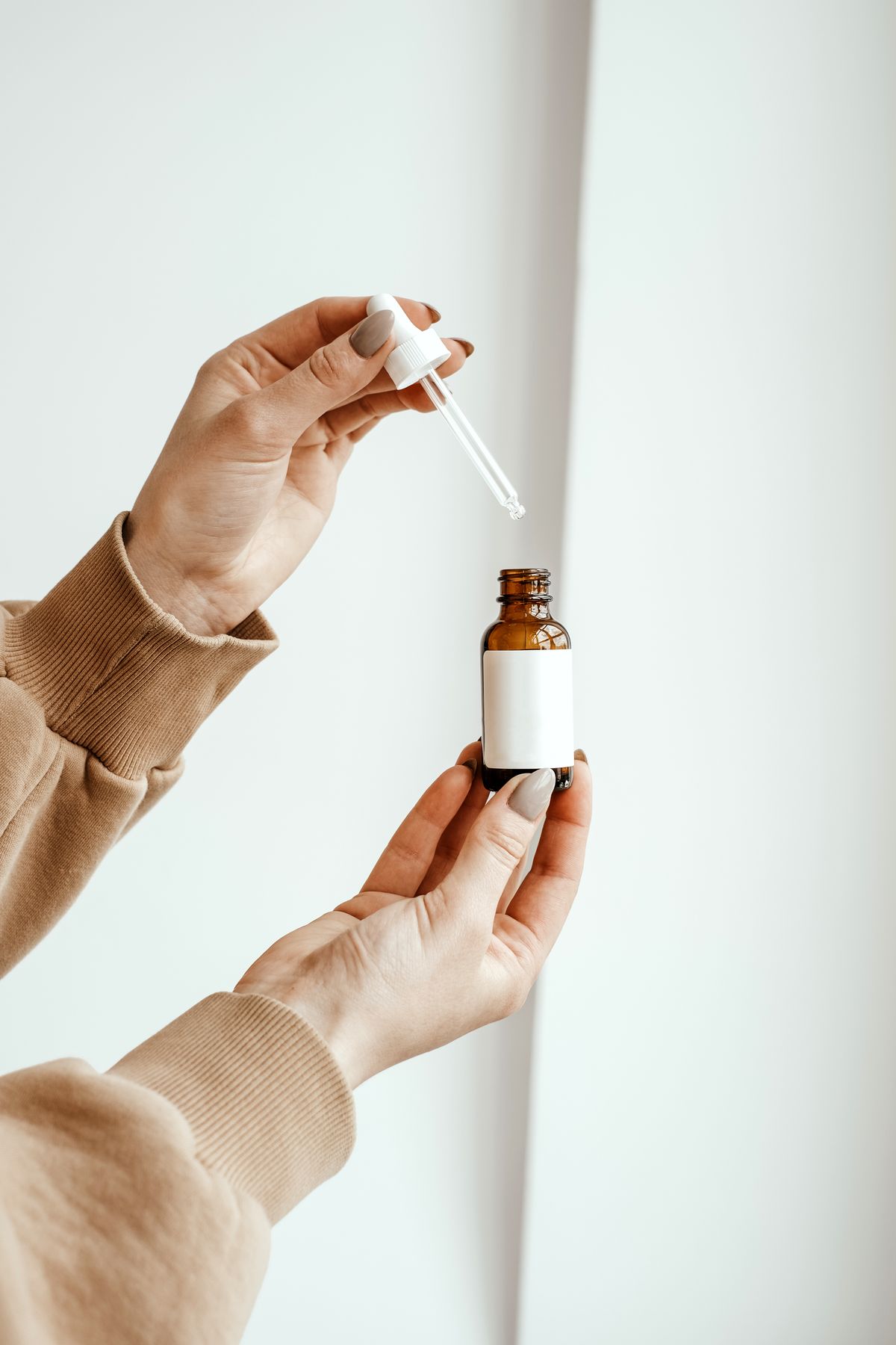 Hands holding an amber glass treatment bottle with a dropper