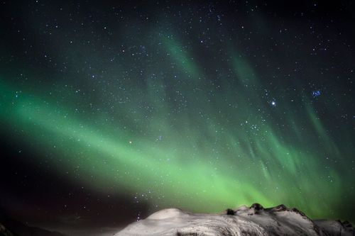 Free Captivating view of the Northern Lights over snow-covered mountains in Oslo on a starry winter night. Stock Photo