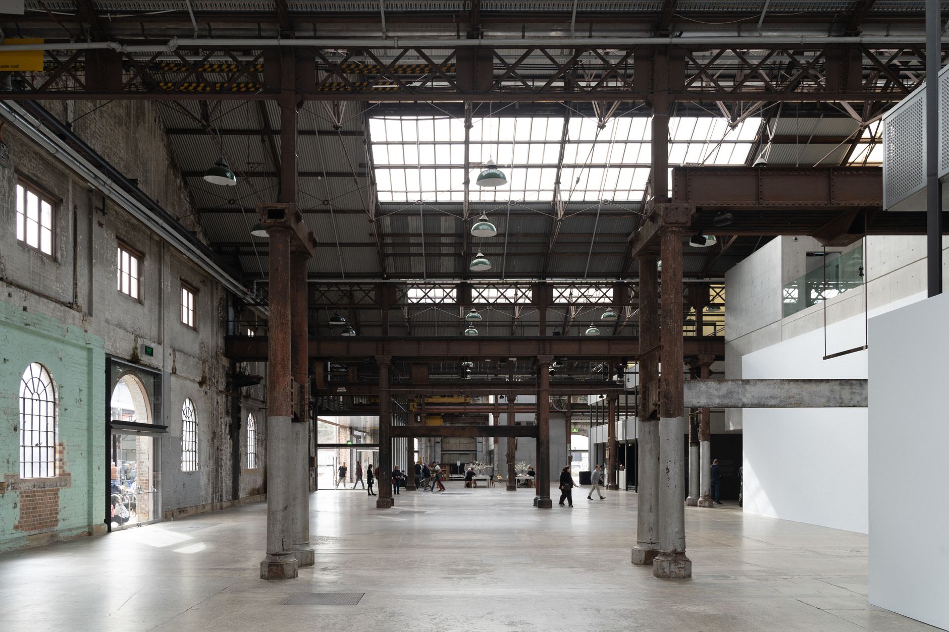 A spacious, light-filled industrial warehouse in Sydney with exposed beams and people walking.