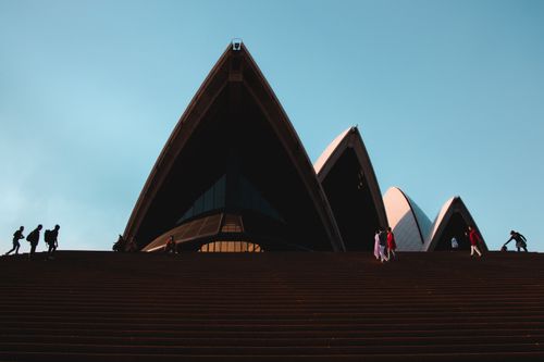 Free Silhouette of the Sydney Opera House with people on stairs under a clear blue sky. Stock Photo